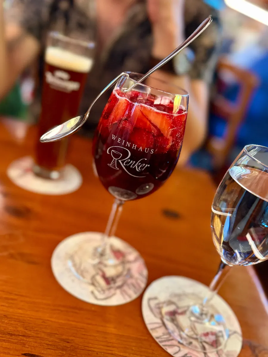 Rotwein im Renker-Glas neben einem frisch gezapften Bier auf dem Holztisch